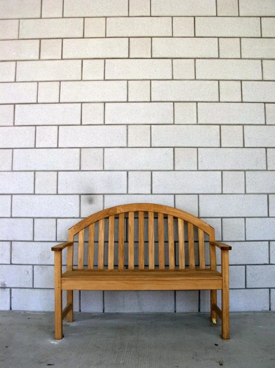 a bench outside against a brick wall