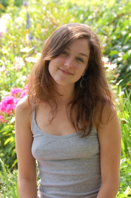 a beautiful young woman sitting in front of flowers