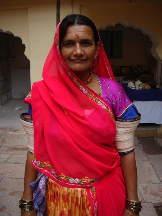 a woman with a big smile stands outside in her traditional sari