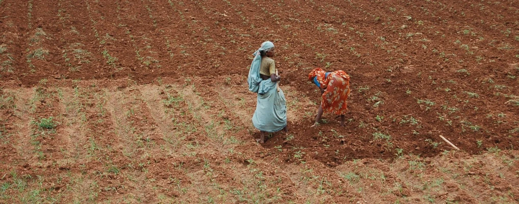 a woman holding a bag while walking in the middle of a field