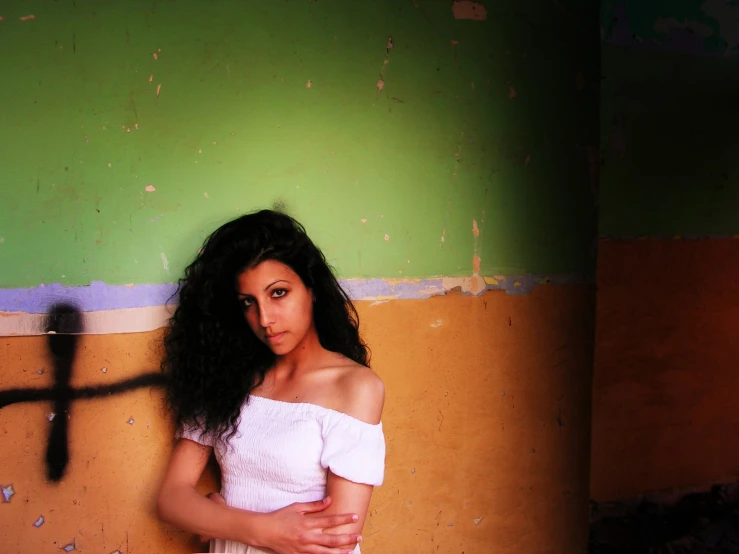 a woman standing near a cross and a wall