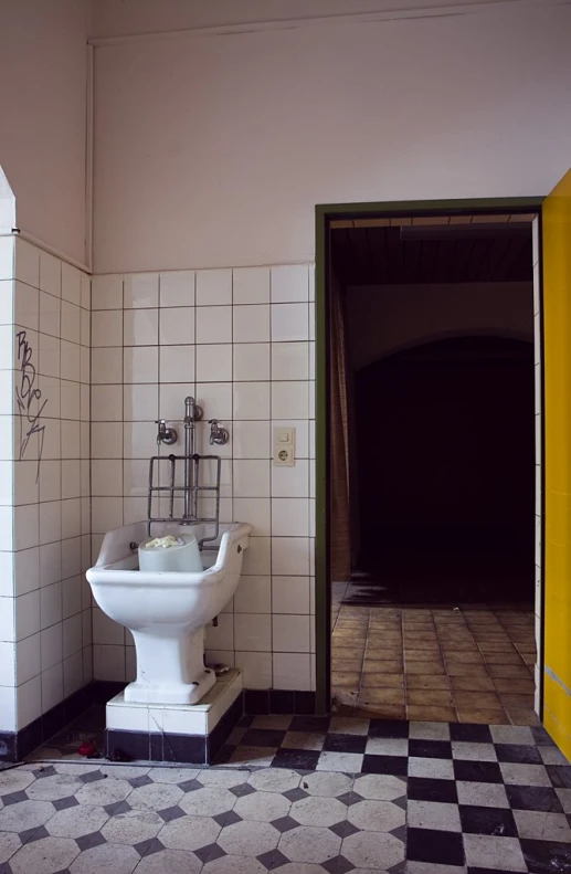 a bathroom with a white toilet and checkered floor