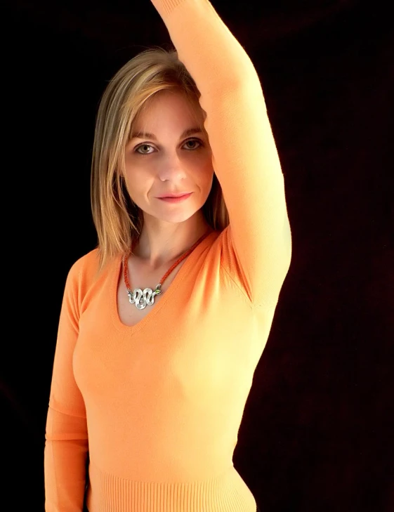 a woman in orange top with her arms above her head