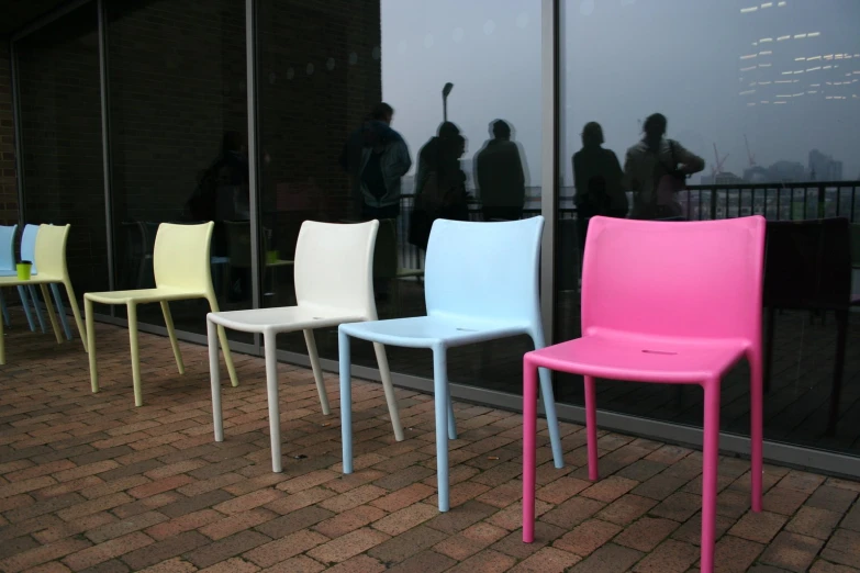 four colorful plastic chairs are set up in front of a store window
