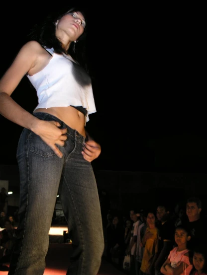 a woman in white top and jeans performing on stage