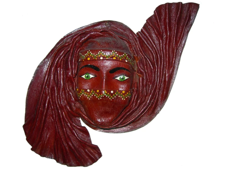 a red mask mounted on a wall and decorated with beads