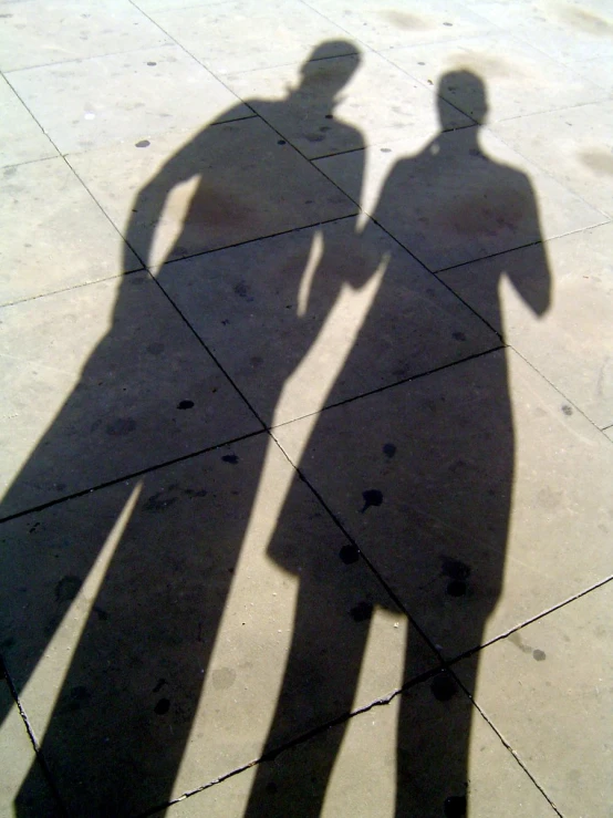 two people standing with their shadows on the ground