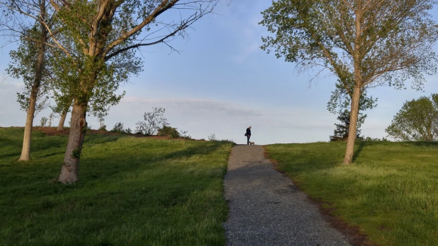 man standing at the end of a road in the middle of a field