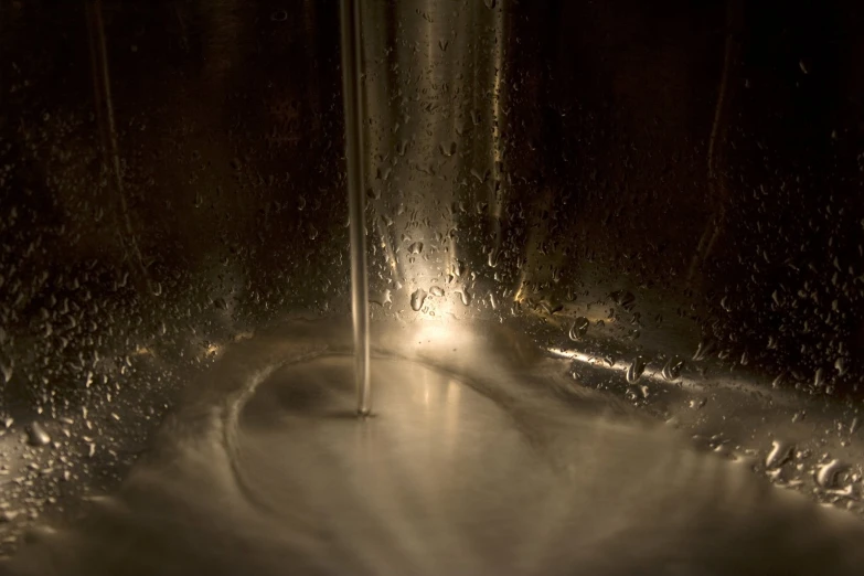 water is flowing out of an empty metal bowl