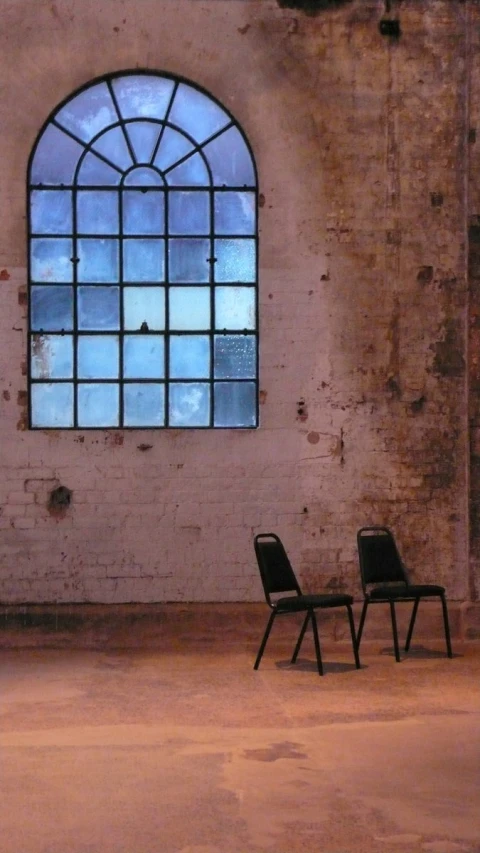 two chairs facing a wall and an empty chair sitting next to the window