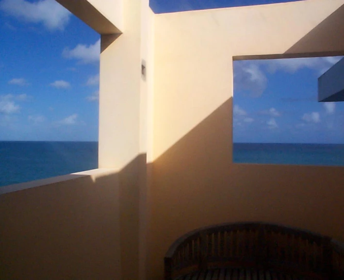 a wooden bench in the shadow of two windows