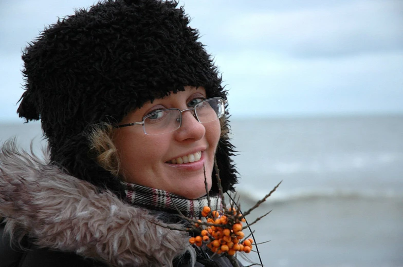 a smiling woman wearing glasses and a black hat