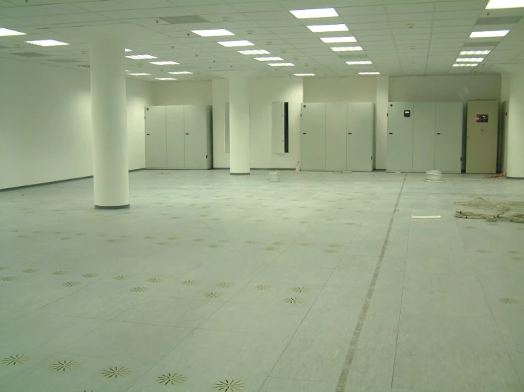 a large room with several white stalls and tiled floors