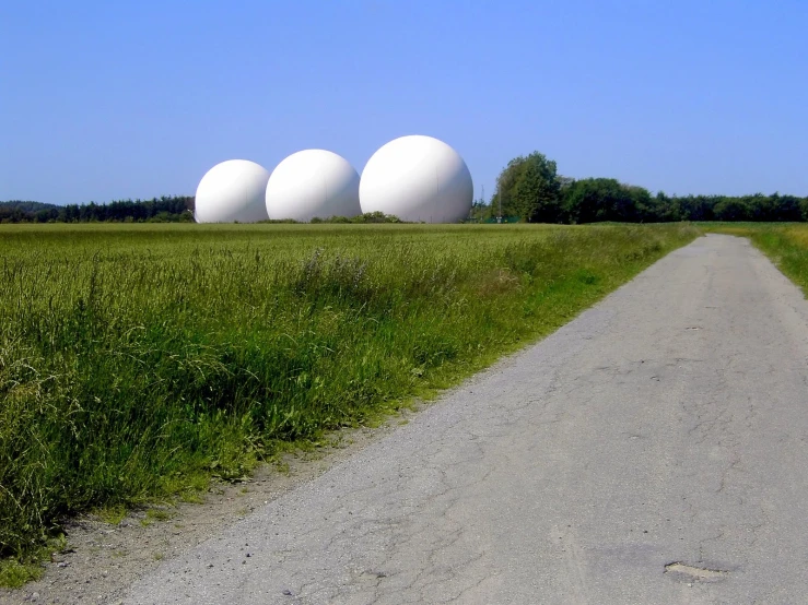 three large white balls set on a roadside