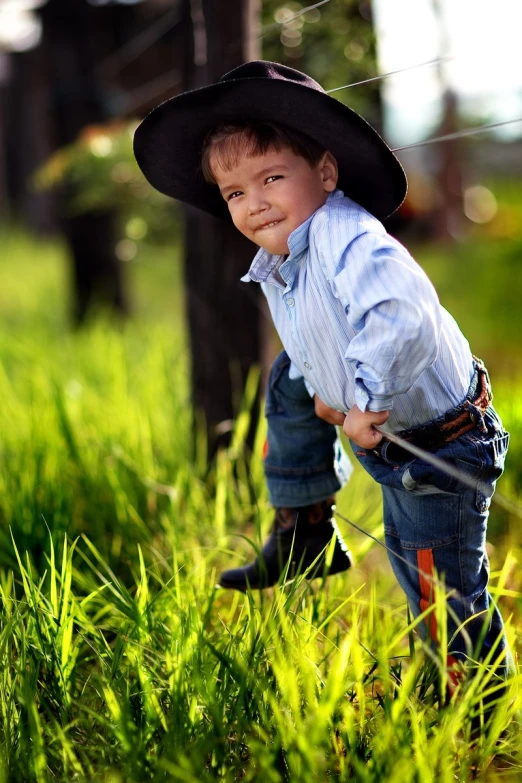a small  wearing a cowboy hat on the grass