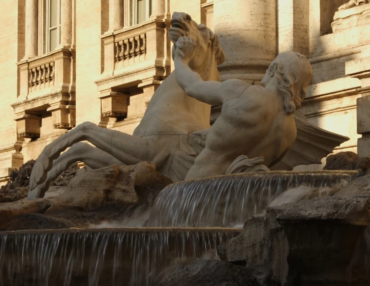 a statue is next to a fountain in front of a building