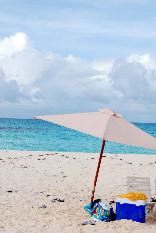 the chair is in front of the umbrella on the beach