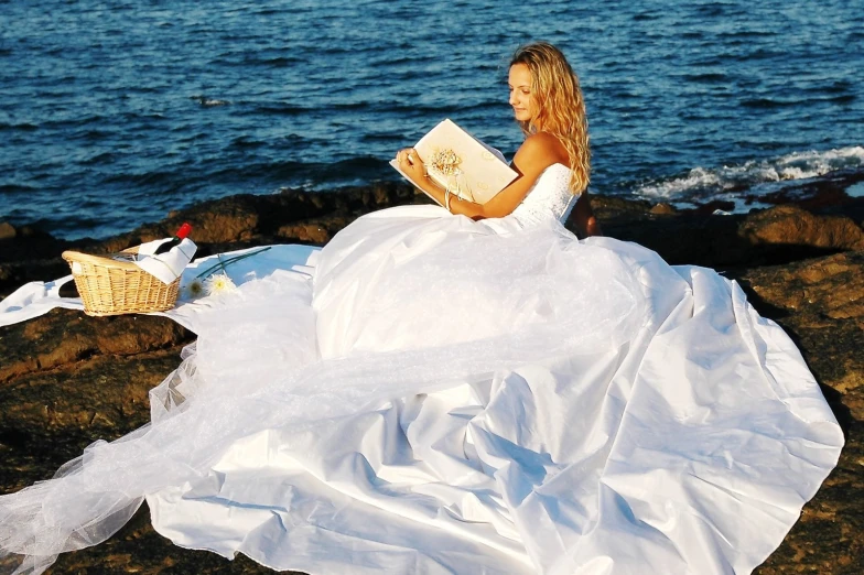 a bride reads her vows from a magazine by the ocean