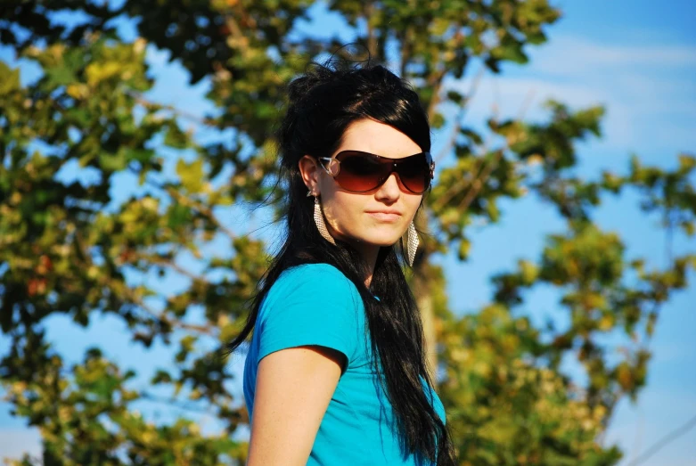 a woman in sunglasses is posing with her back to the camera