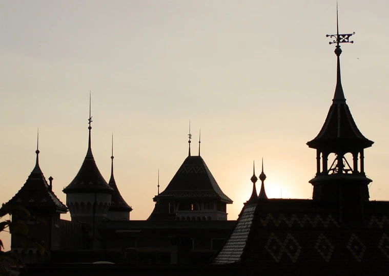 a castle with turrets and spires is silhouetted against the sky