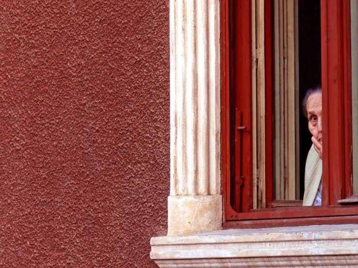 a man wearing white is looking out of a window