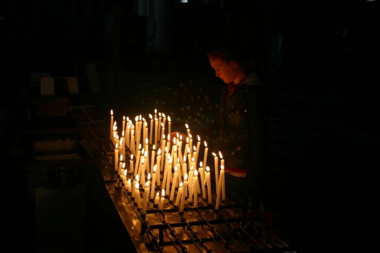 people standing in front of a large group of candles