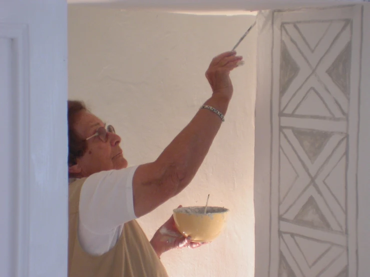 an old woman holding a paintbrush on a wall