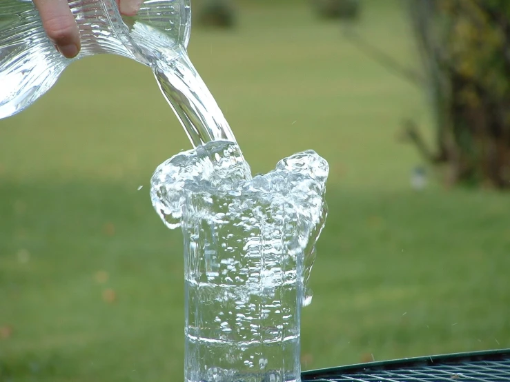 a hand that is pouring water into a glass