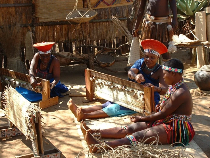 a group of people on wooden chairs in front of hut