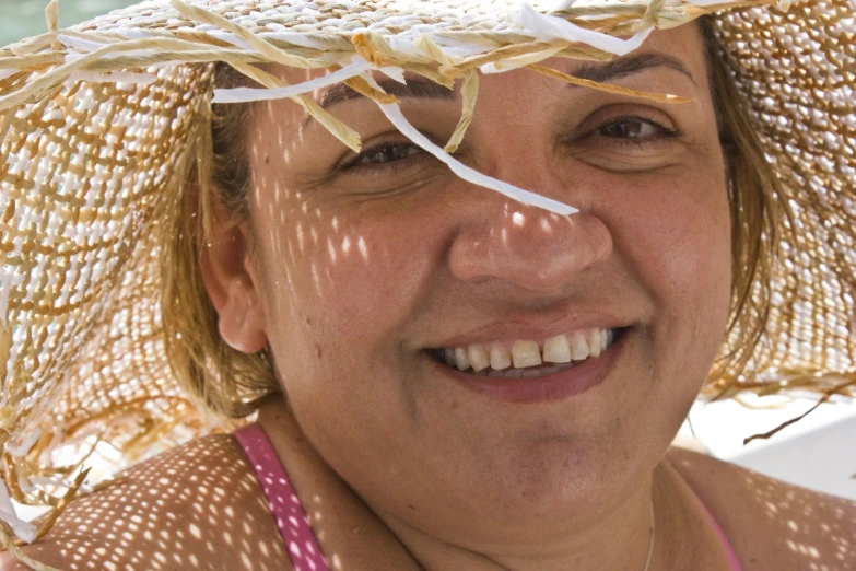 an older woman smiles wearing a straw hat