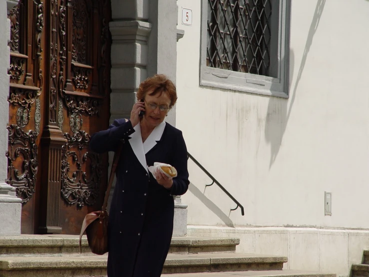 the woman in black is holding a cell phone and eating