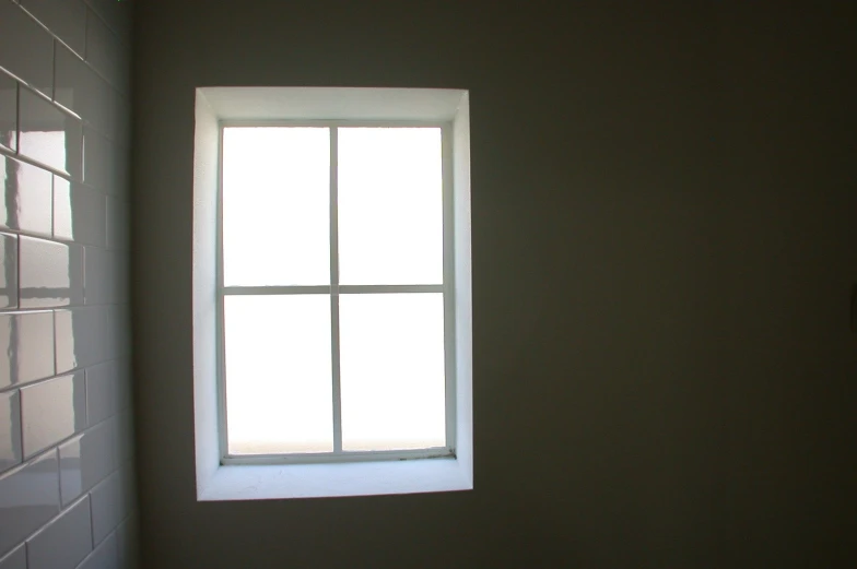 a bathroom window with white tiles and white walls