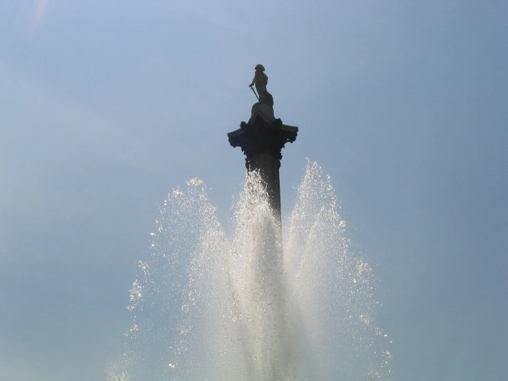 a statue and water spouting from a large pond