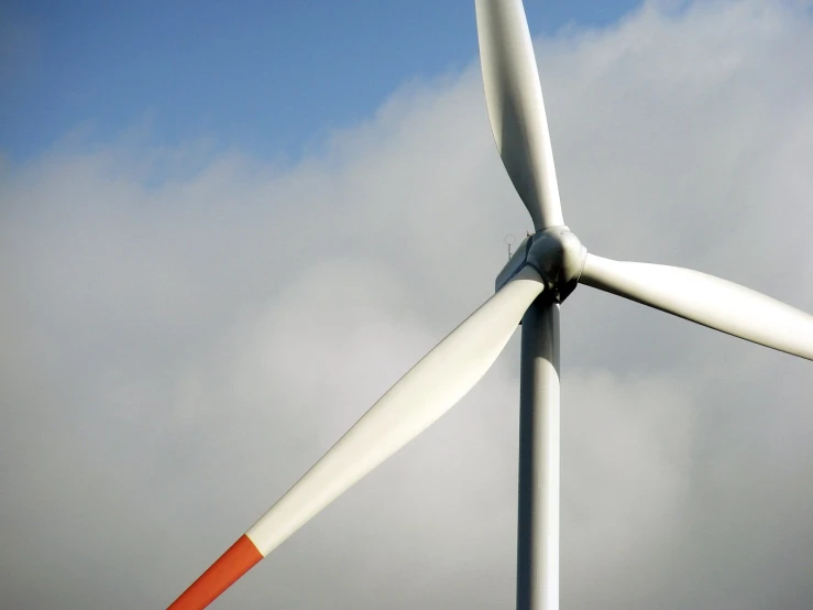 a wind turbine with two blades spinning through a cloudy sky