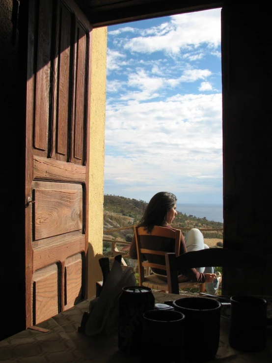 there is a woman that is sitting in a chair and looking out the window