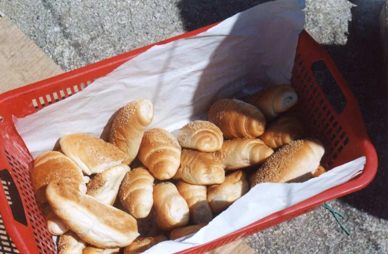 a red basket full of bread rolls sitting on the floor