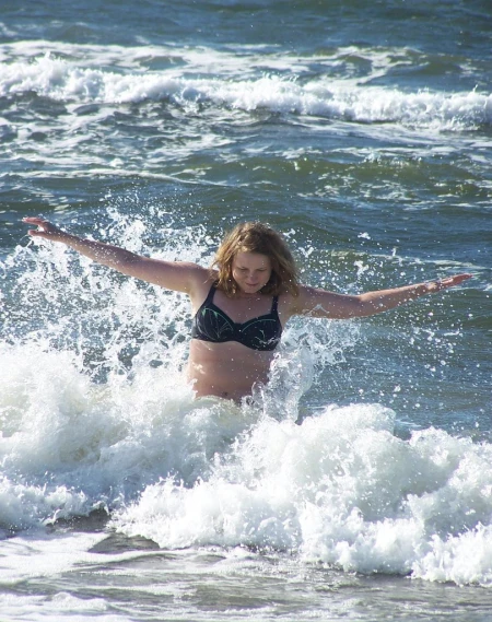 a woman wearing a bikini splashes water in a body of water