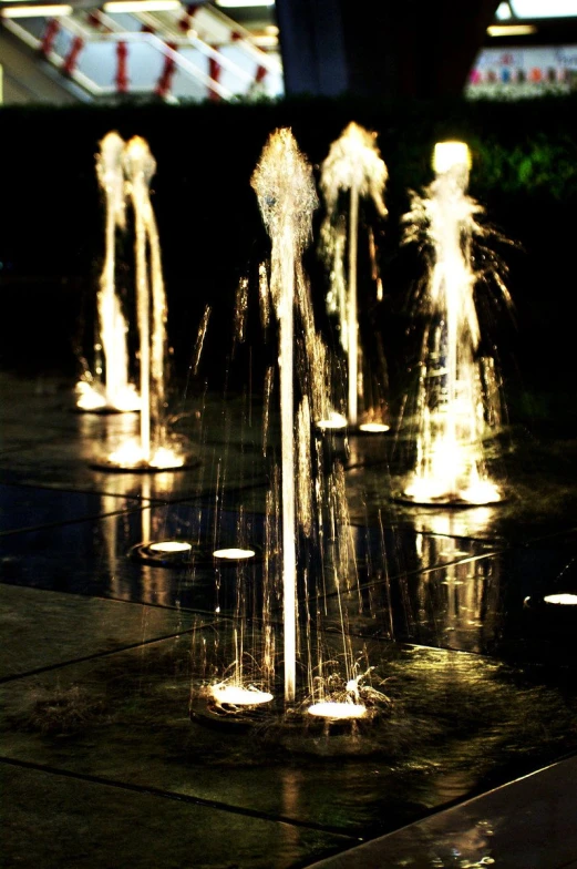 a close up of four fountains spewing water on a dark surface