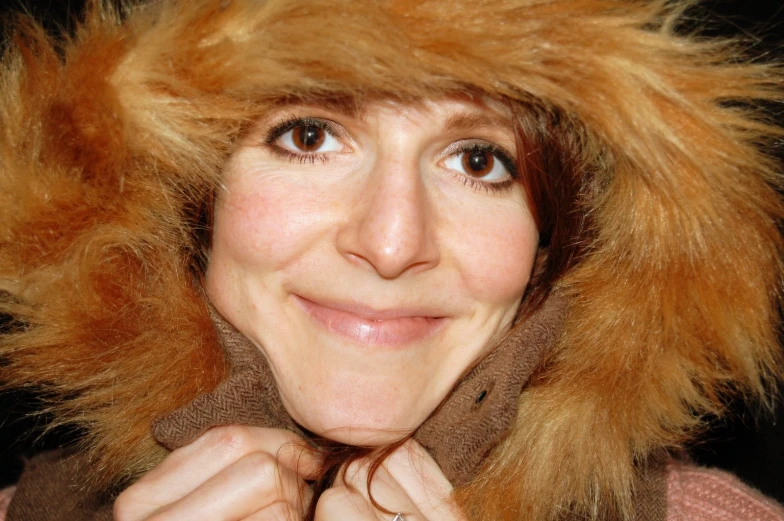 a woman with a furry hood smiling with her hair up