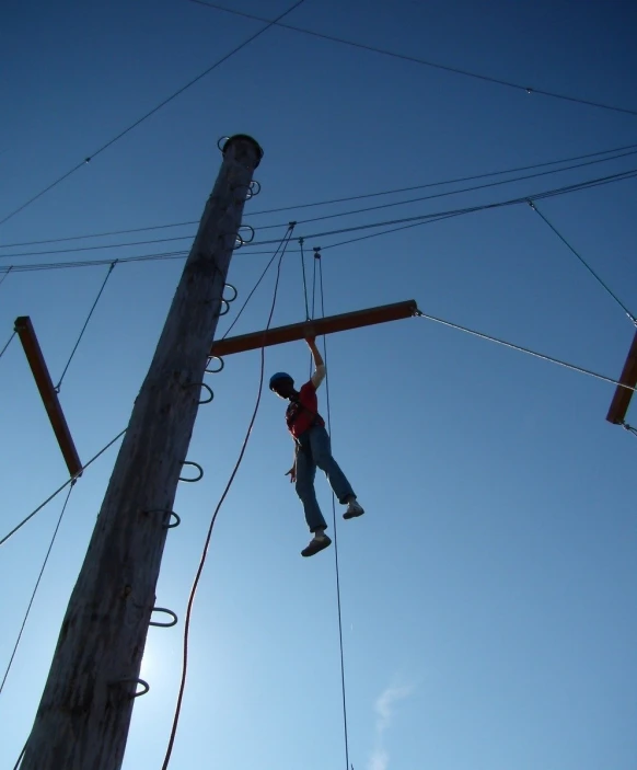 a young man climbing a zip line from an electric utility pole