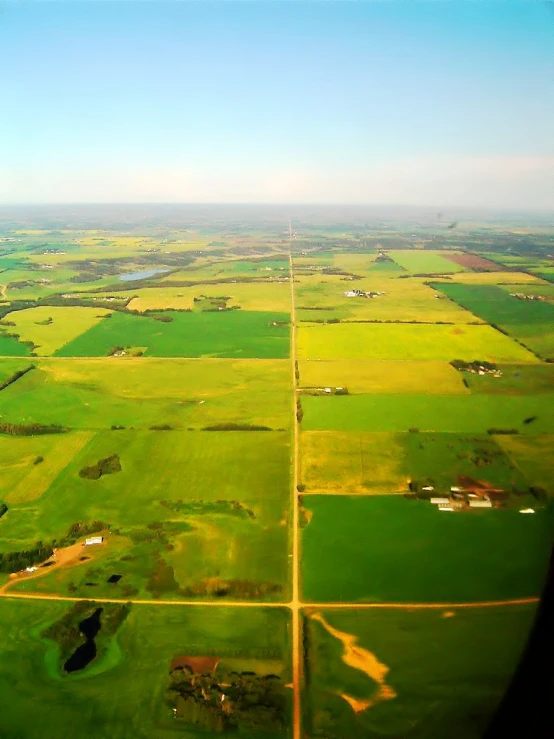 an aerial view from the airplane looking down on green fields