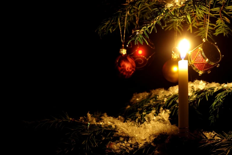 a candle lit up with holiday ornaments and lights