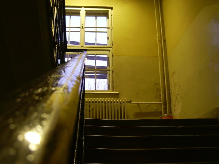 a stairwell leading to a large window with some light on