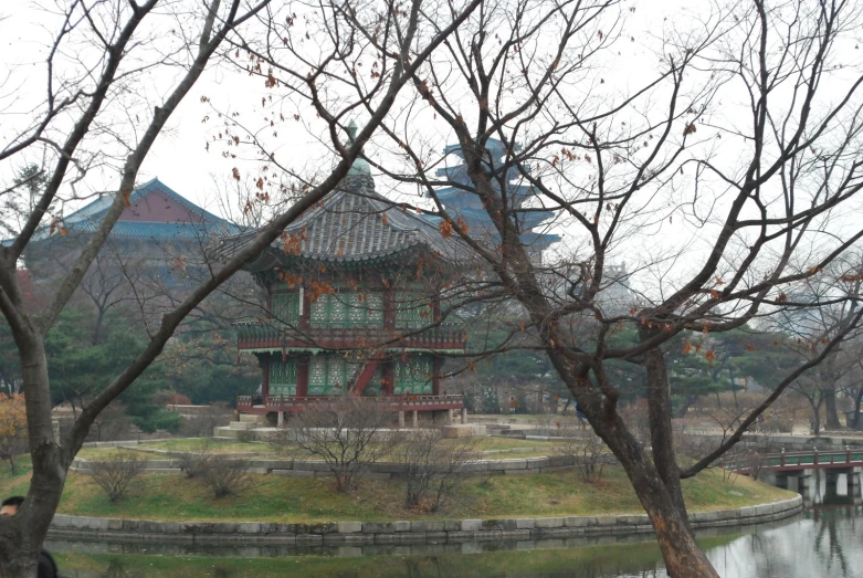 an asian style structure near a body of water with a bridge crossing it