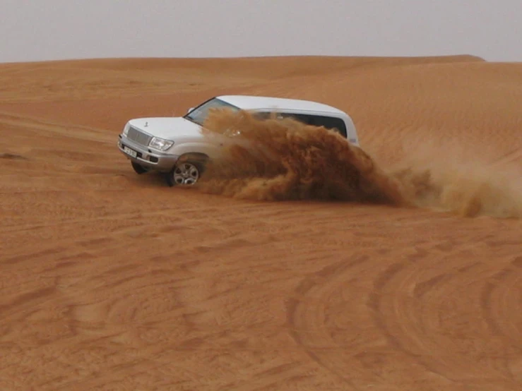 a white truck with an open hood and dust on the ground in the desert