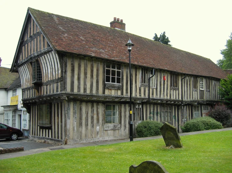 a very old wooden building with a couple of tombstones in the foreground