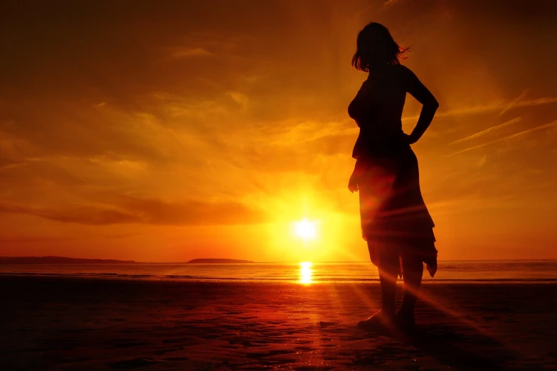 a silhouette po of a woman standing in front of the sun