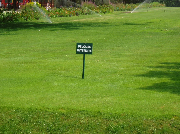 a sign is in the green field spraying water