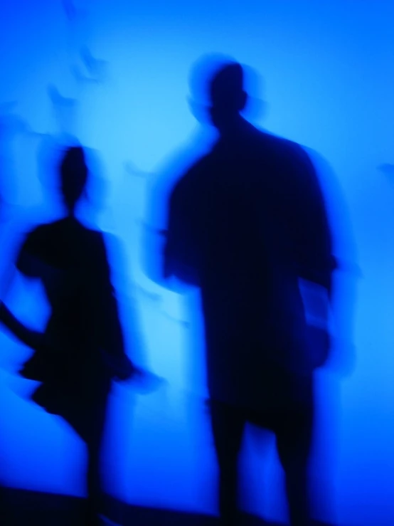 some people standing near a blue wall and shadows