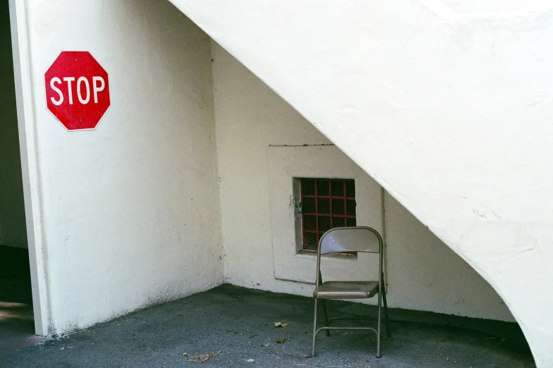 an empty chair sits against the wall behind a stop sign